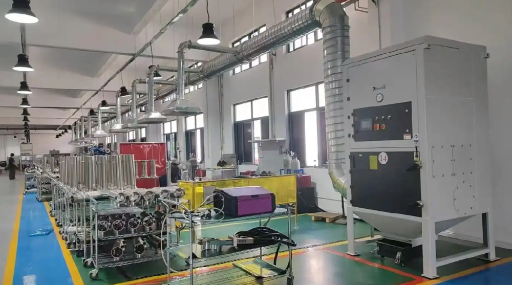 工人操作小型布袋除尘器进行焊接烟尘收集的车间实景